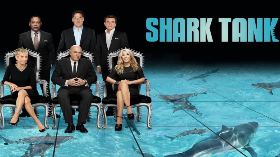 Shark Tank promo photo showing six main sharks seated and standing above a shark tank with the words 