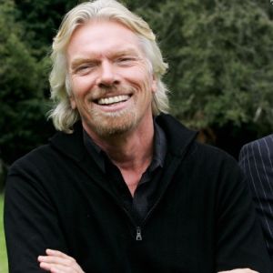 Richard Branson smiling with arms crossed, wearing a black top