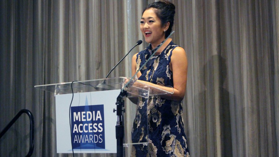 Atypical's Amy Okuda standing at a podium with the sign Media Access Awards