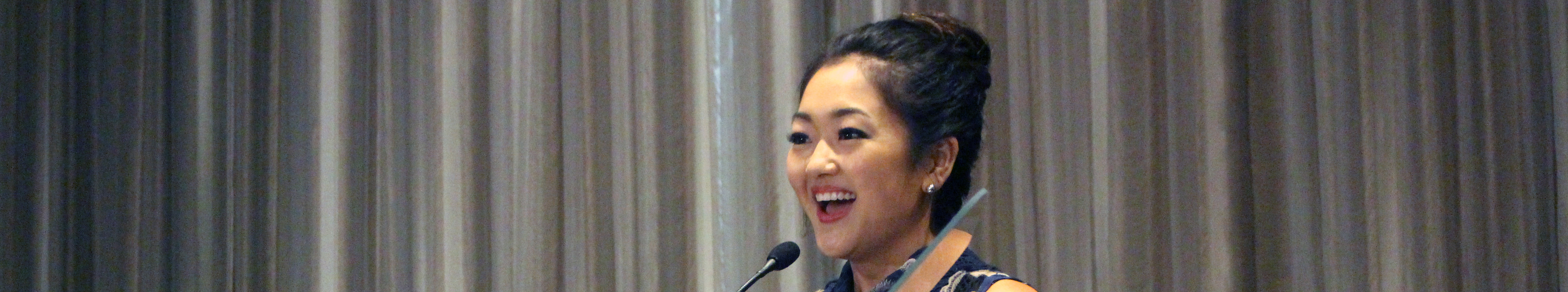 Atypical's Amy Okuda standing at a podium with the sign Media Access Awards