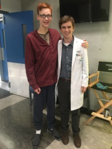 Coby Bird and Freddie Highmore standing and posing on set for the camera 