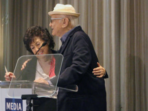 Fern Field and Norman Lear hugging behind the poidum