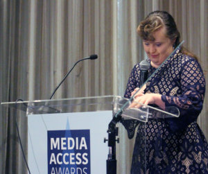 Jamie Brewer tanding at a podium with the sign Media Access Awards