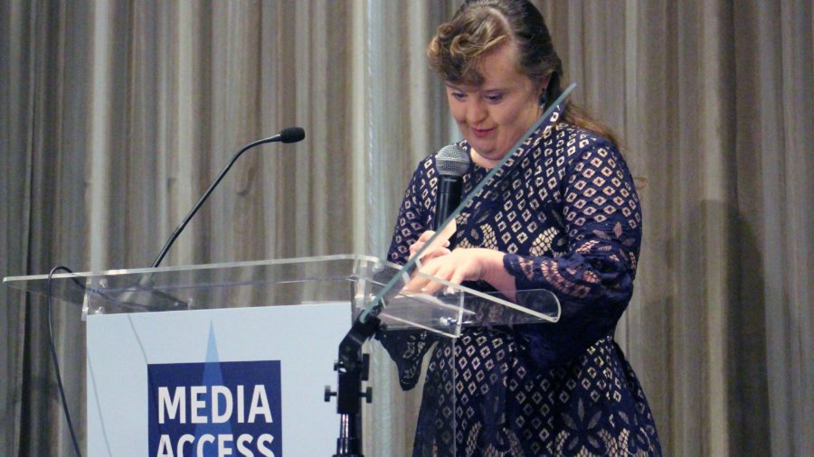 Jamie Brewer tanding at a podium with the sign Media Access Awards