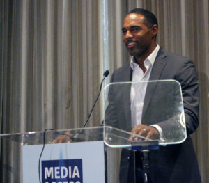 Jason George standing at a podium with the sign Media Access Awards