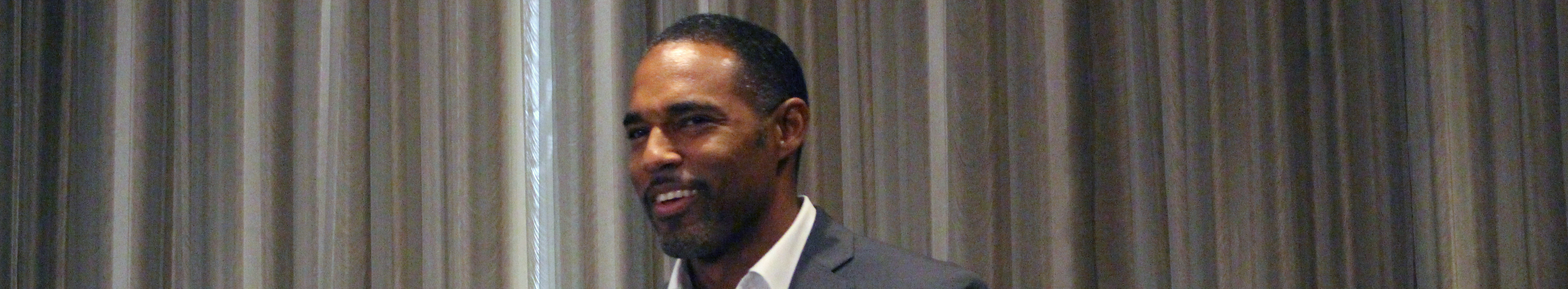 Jason George standing at a podium with the sign Media Access Awards