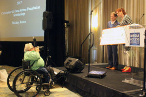 Mickey Rowe posing for photo with Katy Sullivan, holding award check, while having photo taken