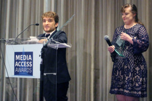 Nic Novicki and Jamie Brewer standing at a podium with the sign Media Access Awards