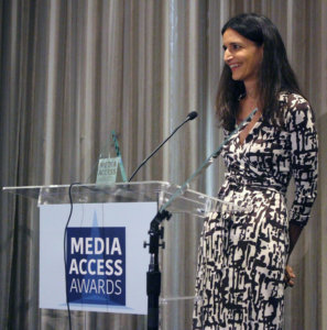 Atypical's Robia Rashid standing at a podium with the sign Media Access Awards