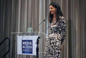 Atypical's Robia Rashid standing at a podium with the sign Media Access Awards