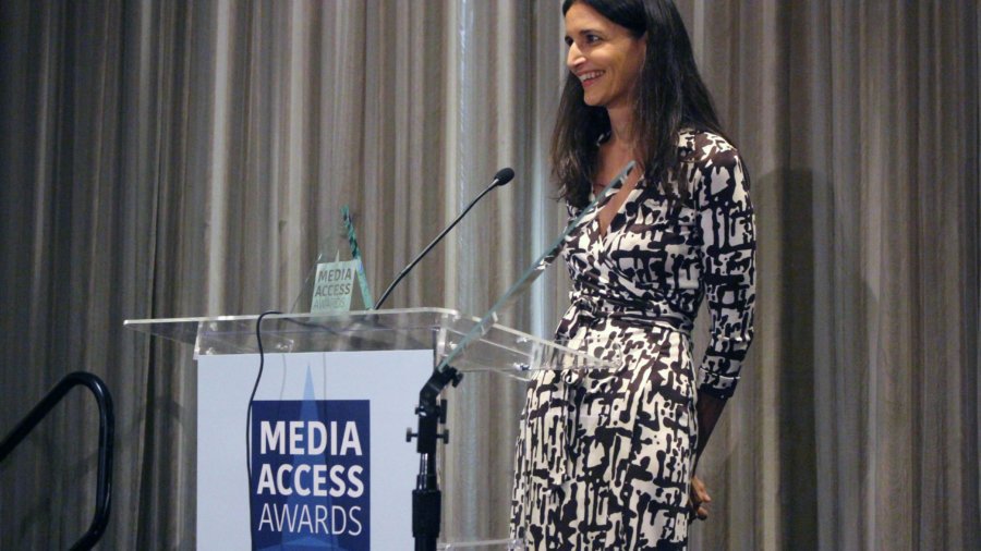 Atypical's Robia Rashid standing at a podium with the sign Media Access Awards