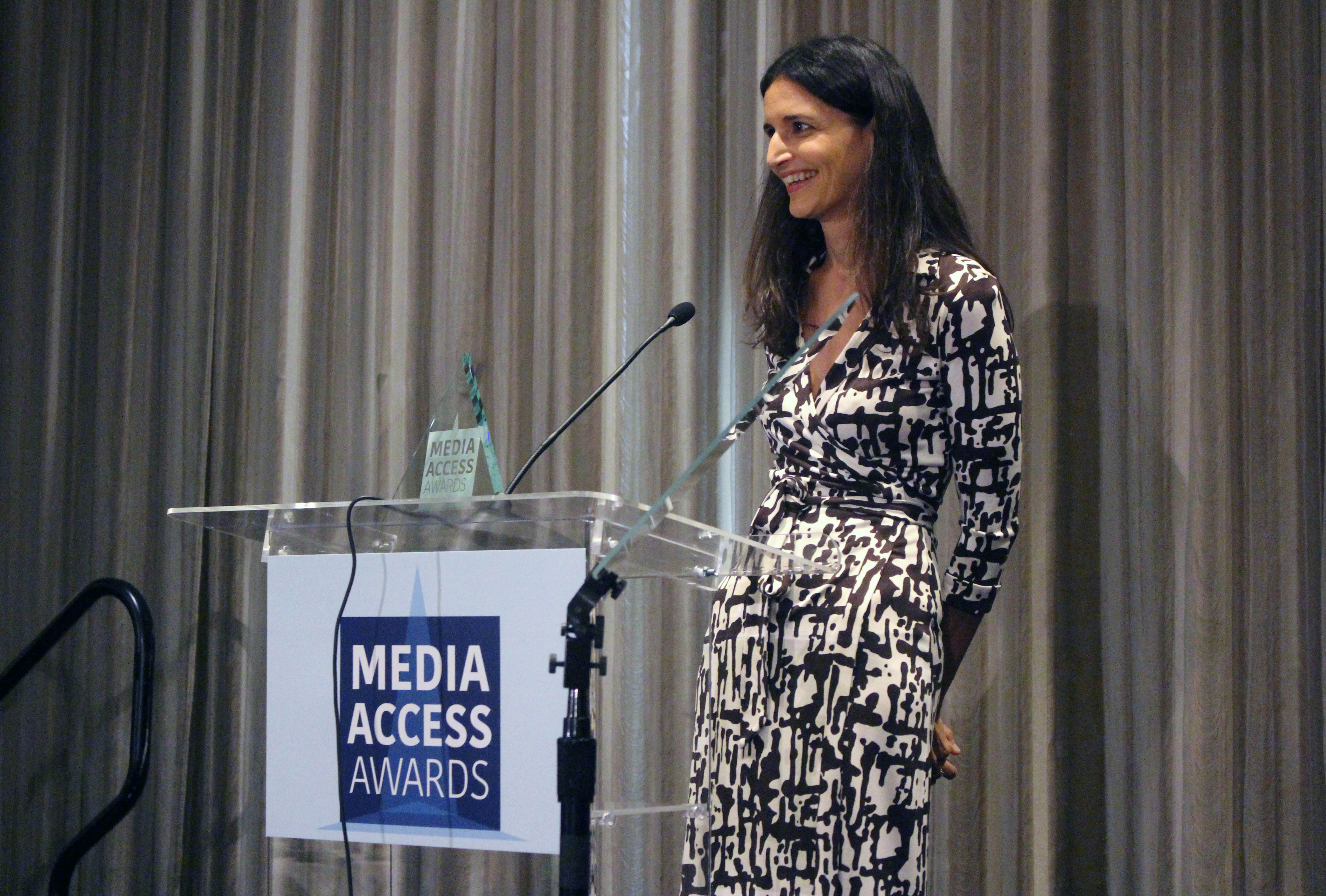 Atypical's Robia Rashid standing at a podium with the sign Media Access Awards