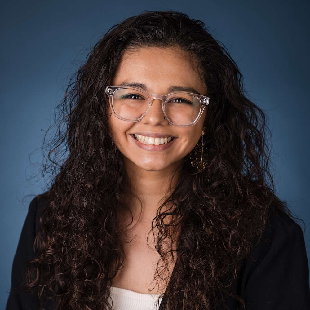 Isabella Vargas smiling headshot in front of a blue gradient backdrop