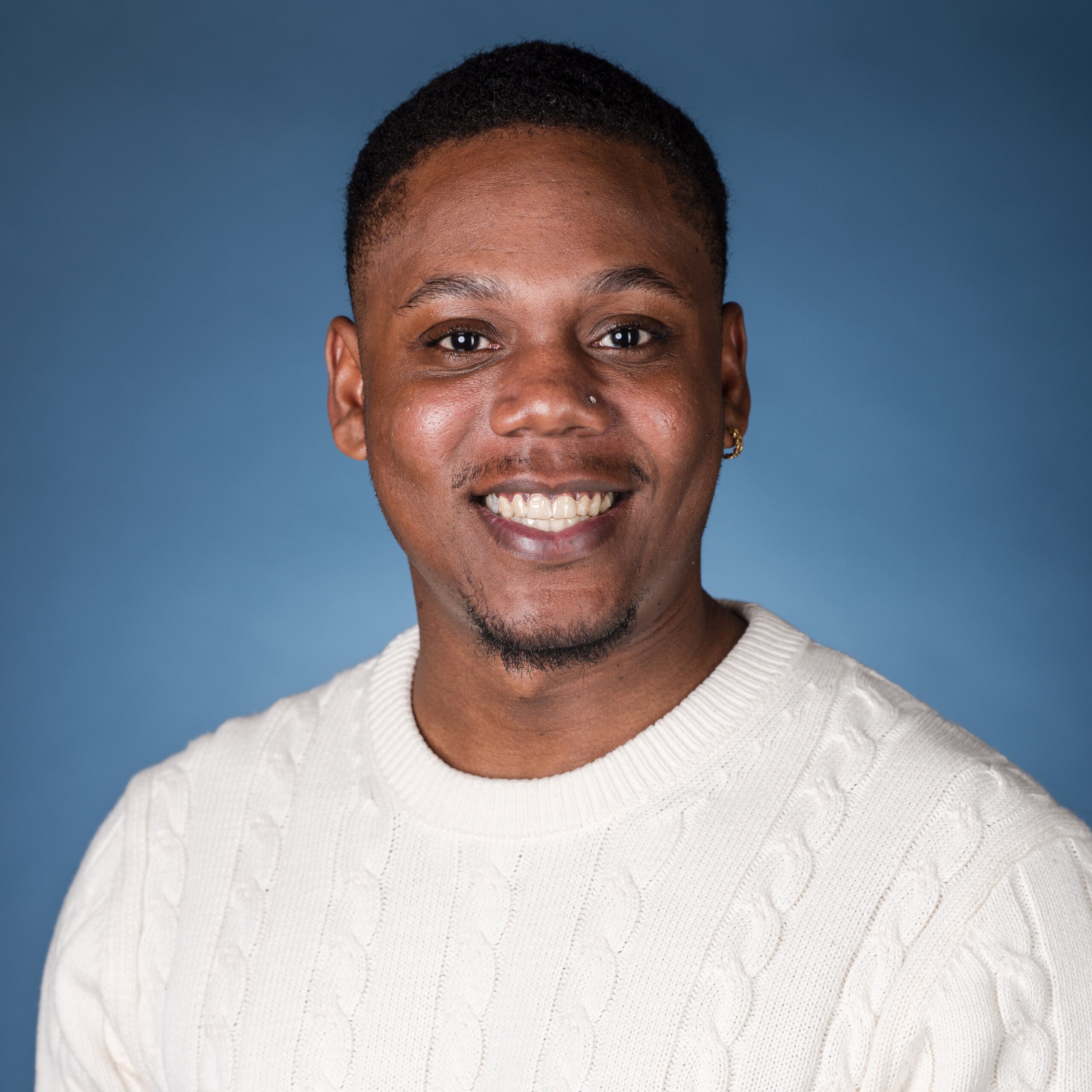 Jacquill Moss smiling headshot in front of a blue gradient backdrop