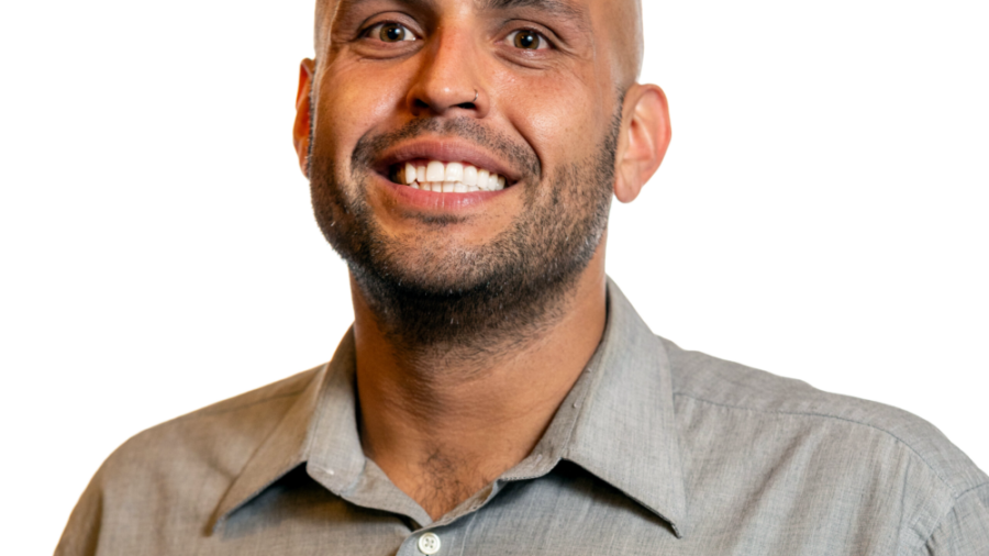 Phillip Saldana smiling headshot wearing a bluish-grey dress shirt