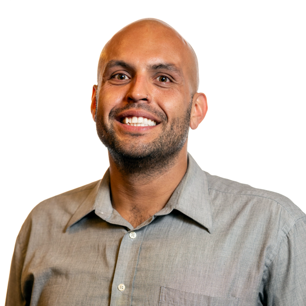Phillip Saldana smiling headshot wearing a bluish-grey dress shirt
