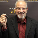 headshot of Stan Goldman smiling and holding a pen