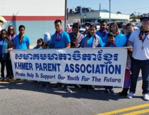 A group of people holding a banner reading "Khmer Parent Association - please help to support our youth for the future."