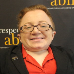 RespectAbility fellow Adrienne Baez smiling in front of the RespectAbility banner