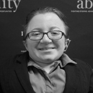 RespectAbility fellow Adrienne Baez smiling in front of the RespectAbility banner