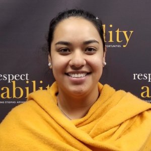 RespectAbility fellow Juliet Arcila Rojas smiling in front of the RespectAbility banner