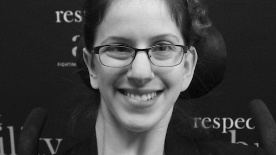 RespectAbility fellow Sarah Bram smiling in front of the RespectAbility banner