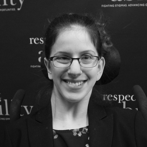 RespectAbility fellow Sarah Bram smiling in front of the RespectAbility banner