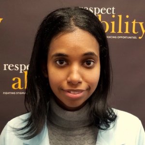 RespectAbility fellow Tameir Yeheyes smiling in front of the RespectAbility banner