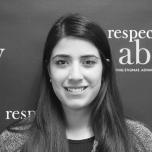 RespectAbility Fellow Ana Lucia Figueroa smiling in front of the RespectAbility banner