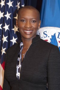 Claudia Gordon standing in front of two flags, smiling.