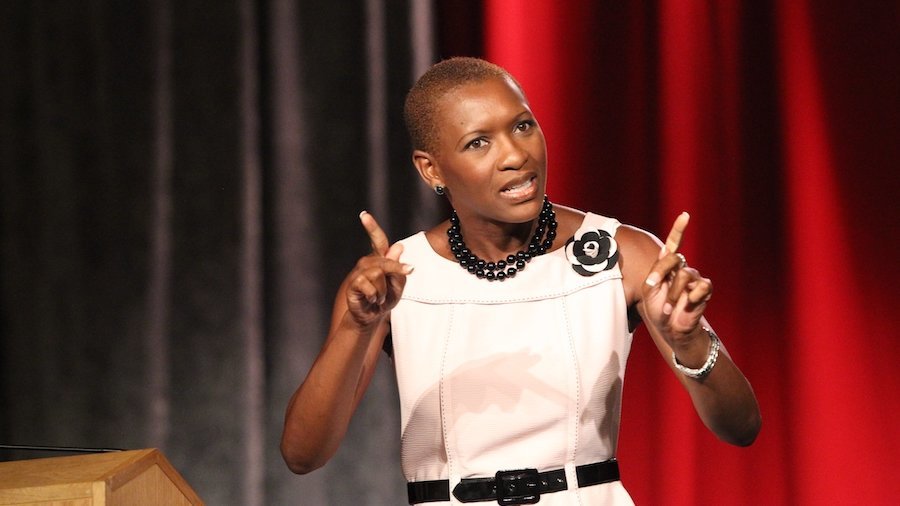 Claudia Gordon giving a speech in front of a curtain