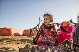 A young girl engages with Elmo at an informal tented settlement near Mafraq, Jordan, in February 2017