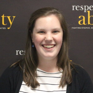 RespectAbility Fellow Emily Counts smiling in front of the RespectAbility banner