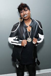 Missy Elliot smiling for the camera, dressed in a black and white outift