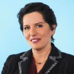 Jeanette Betancourt smiling in front of a blue background