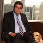 Jim Sinocchi sitting in front of a window with his dog by his side