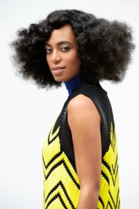 Solange Knowles wearing a black and yellow dress smiling for the camera