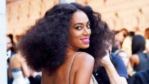 headshot of Solange Knowles wearing a gold dress and pink lipstick