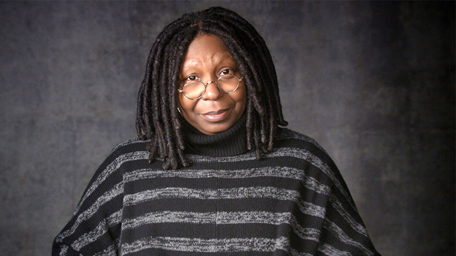 Whoopi Goldberg wearing a black and gray striped sweater facing the camera