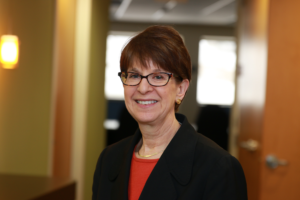 Elaine Katz smiling in front of a blurred background