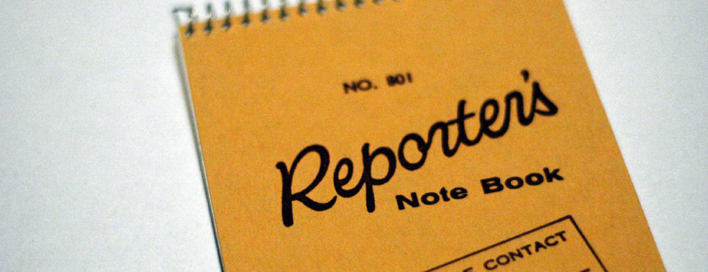 A notebook that says "Reporter Note Book" on the cover