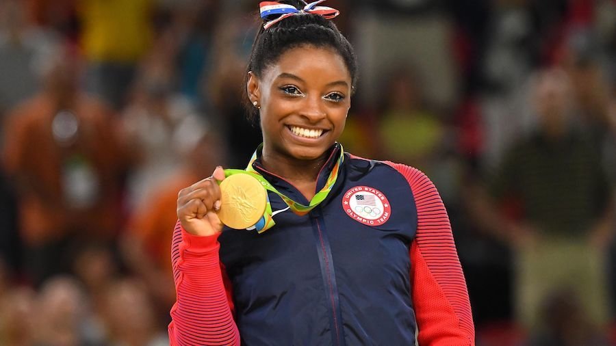 Simone Biles holding her gold medal at the Olympics