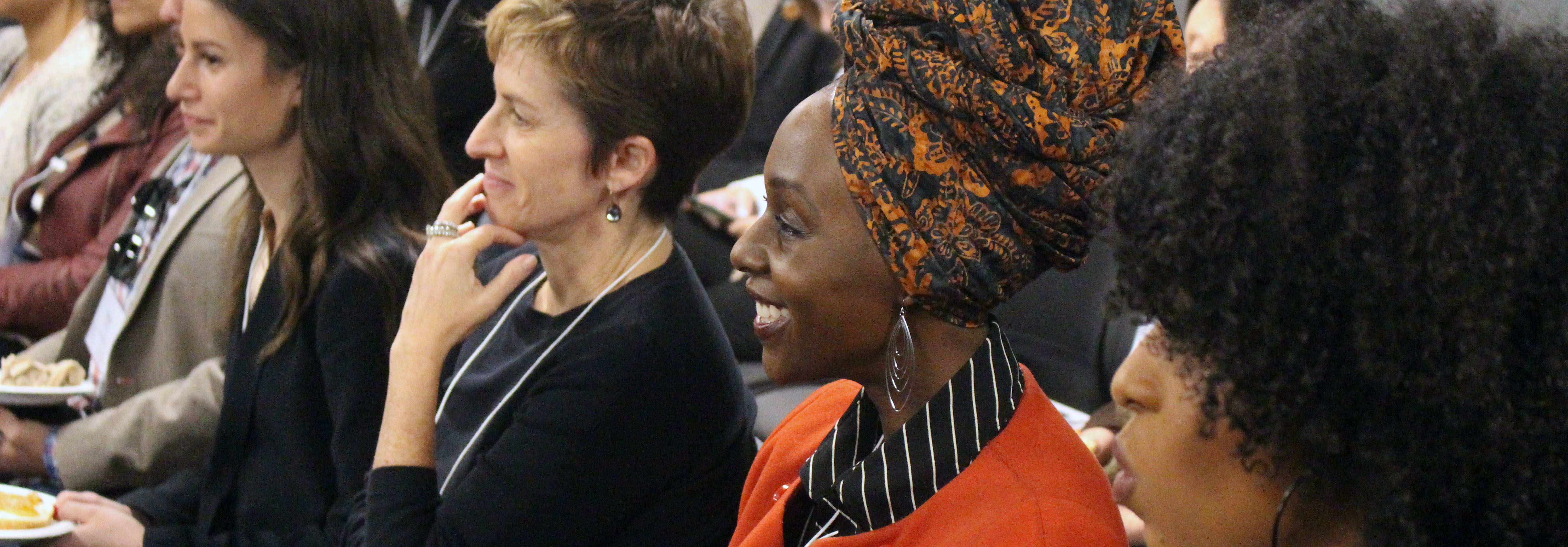 Audience members smiling and paying attention to the speakers