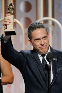Lee Unkrich on stage holding an Oscar award
