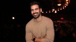 Nyle DiMarco smiling wearing a brown sweater
