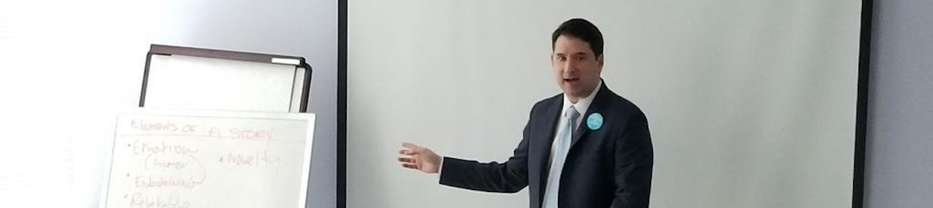 Geoffrey Melada standing in front of the room, pointing to a giant notepad