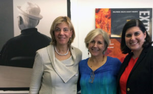 HH&S' Director Kate Folb in between RespectAbility's President Jennifer Laszlo Mizrahi and Communications Director Lauren Appelbaum, all standing and smiling, in front of a picture of Norman Lear