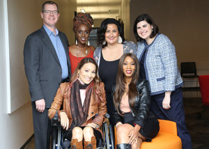 five diverse women and one man standing and seated smiling for the camera