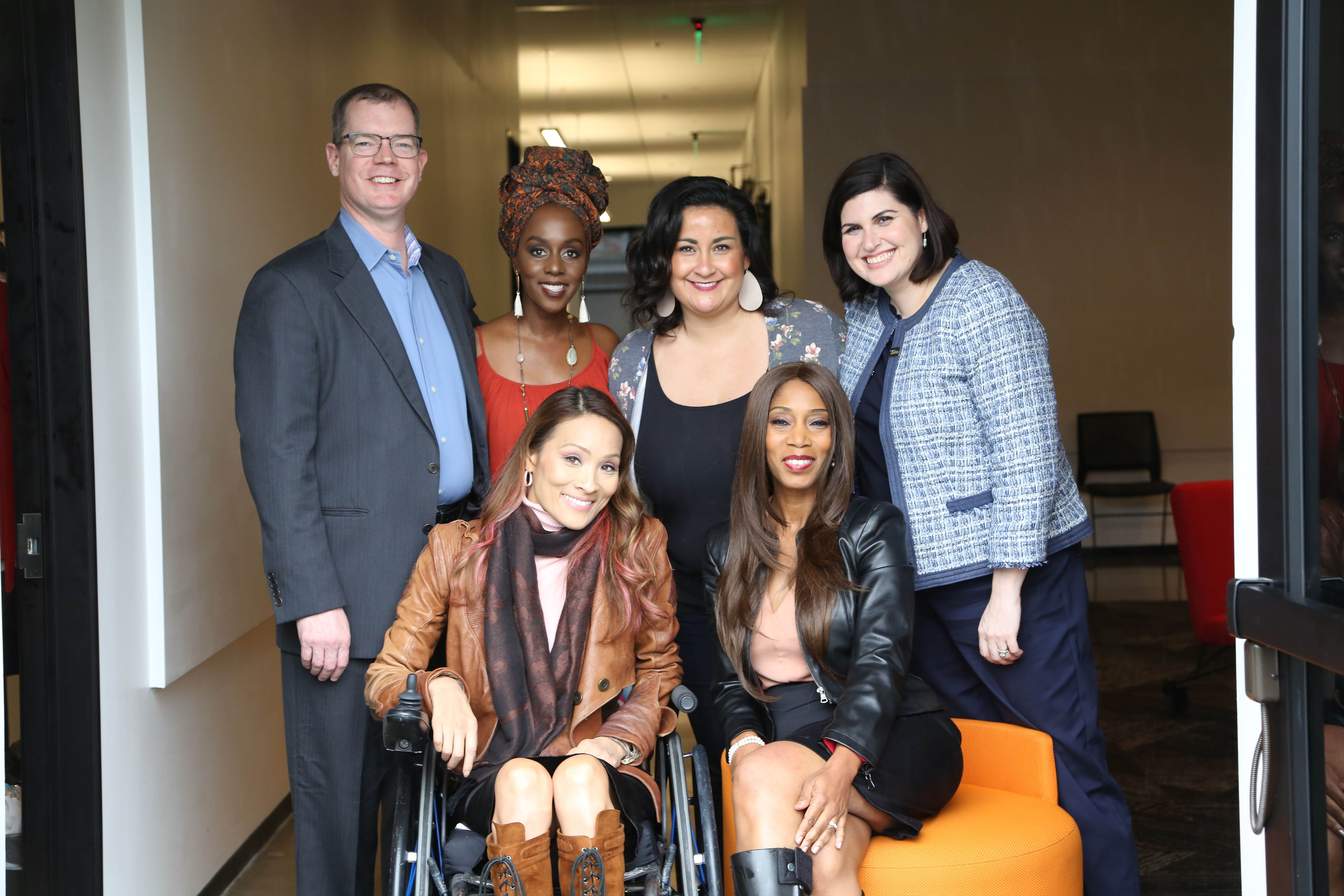 five diverse women and one man standing and seated smiling for the camera