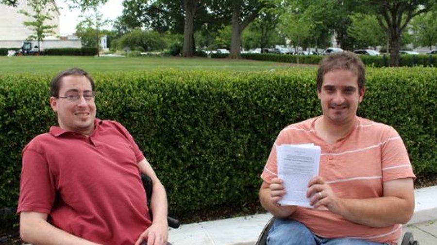 Photo of Justin Chappell and Ben Spangenberg, with Ben holding up a stack of papers
